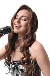 Beautiful young woman with microphone singing on white background