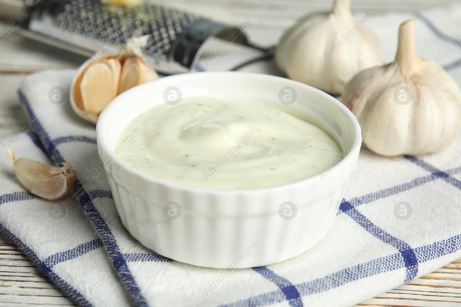 Photo of Composition with bowl of garlic sauce on table