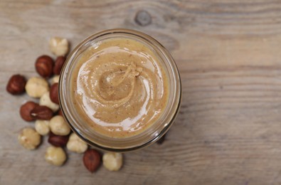 Photo of Tasty hazelnut nut paste in jar on table, top view. Space for text