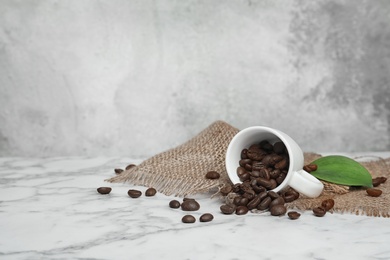 Photo of Ceramic cup with coffee beans on marble table