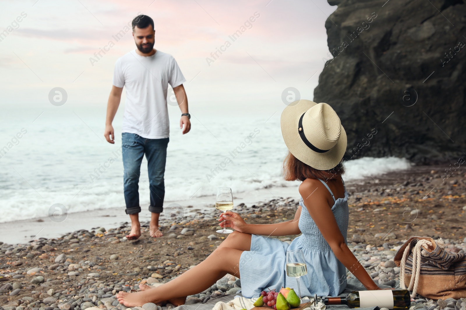 Photo of Young couple having picnic on beach near sea