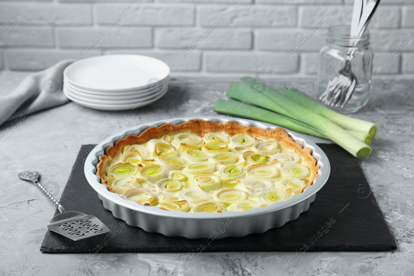 Photo of Freshly baked leek pie served on grey textured table