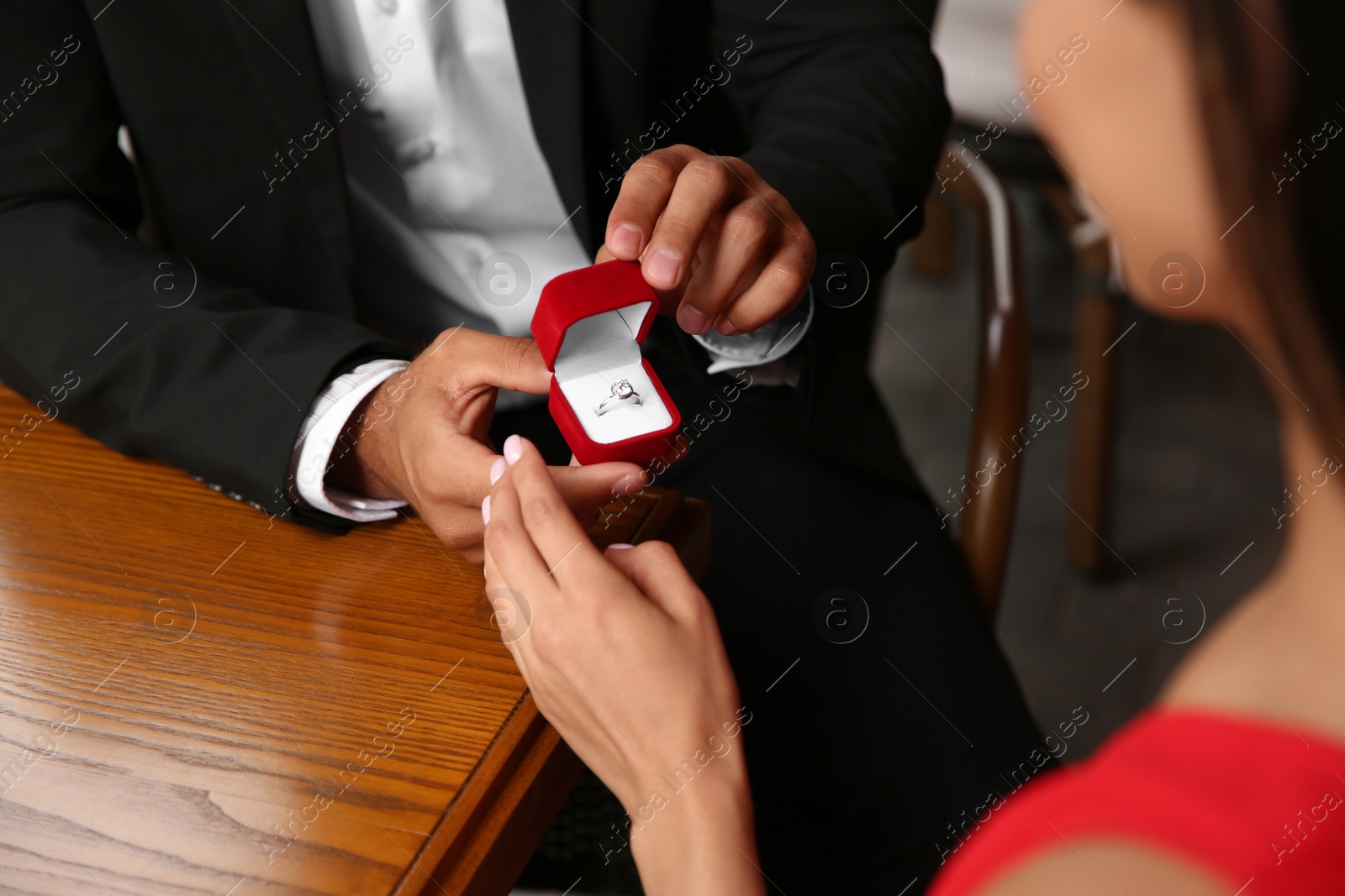 Photo of Man with engagement ring making proposal to his girlfriend at table, closeup