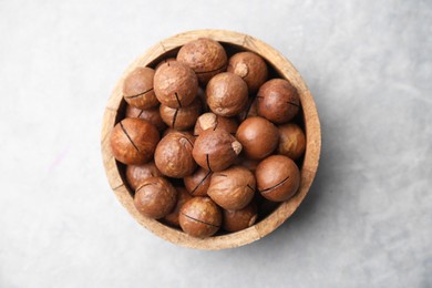 Photo of Delicious macadamia nuts in bowl on light grey table, top view