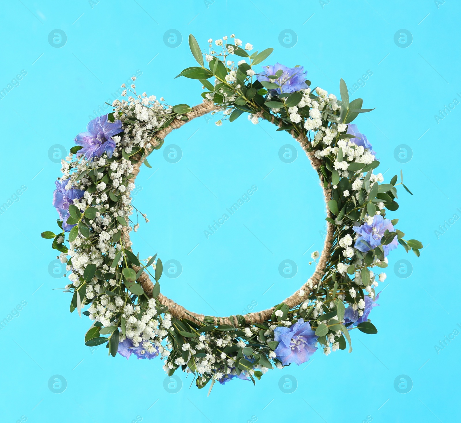 Photo of Beautiful handmade flower wreath on light blue background