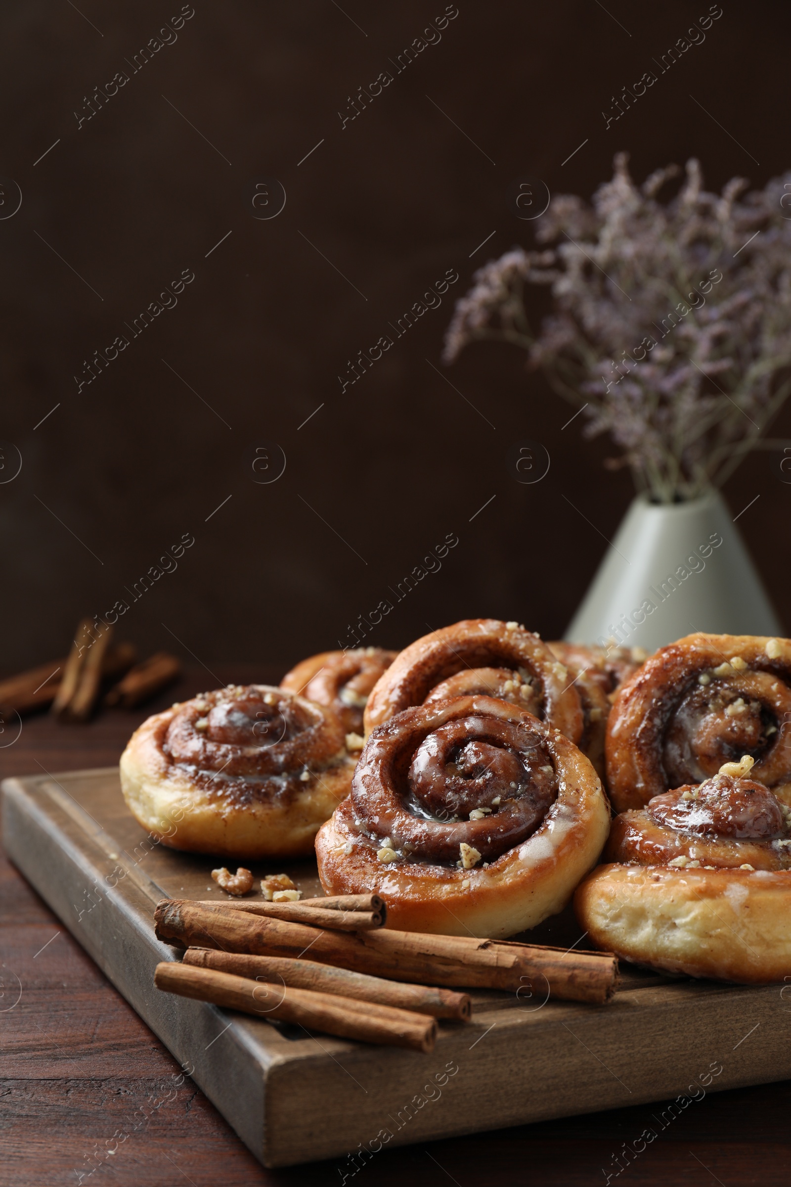 Photo of Tasty cinnamon rolls, sticks and nuts on wooden table