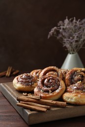 Photo of Tasty cinnamon rolls, sticks and nuts on wooden table