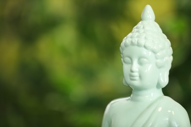 Photo of Buddha statue against blurred green background, closeup. Space for text