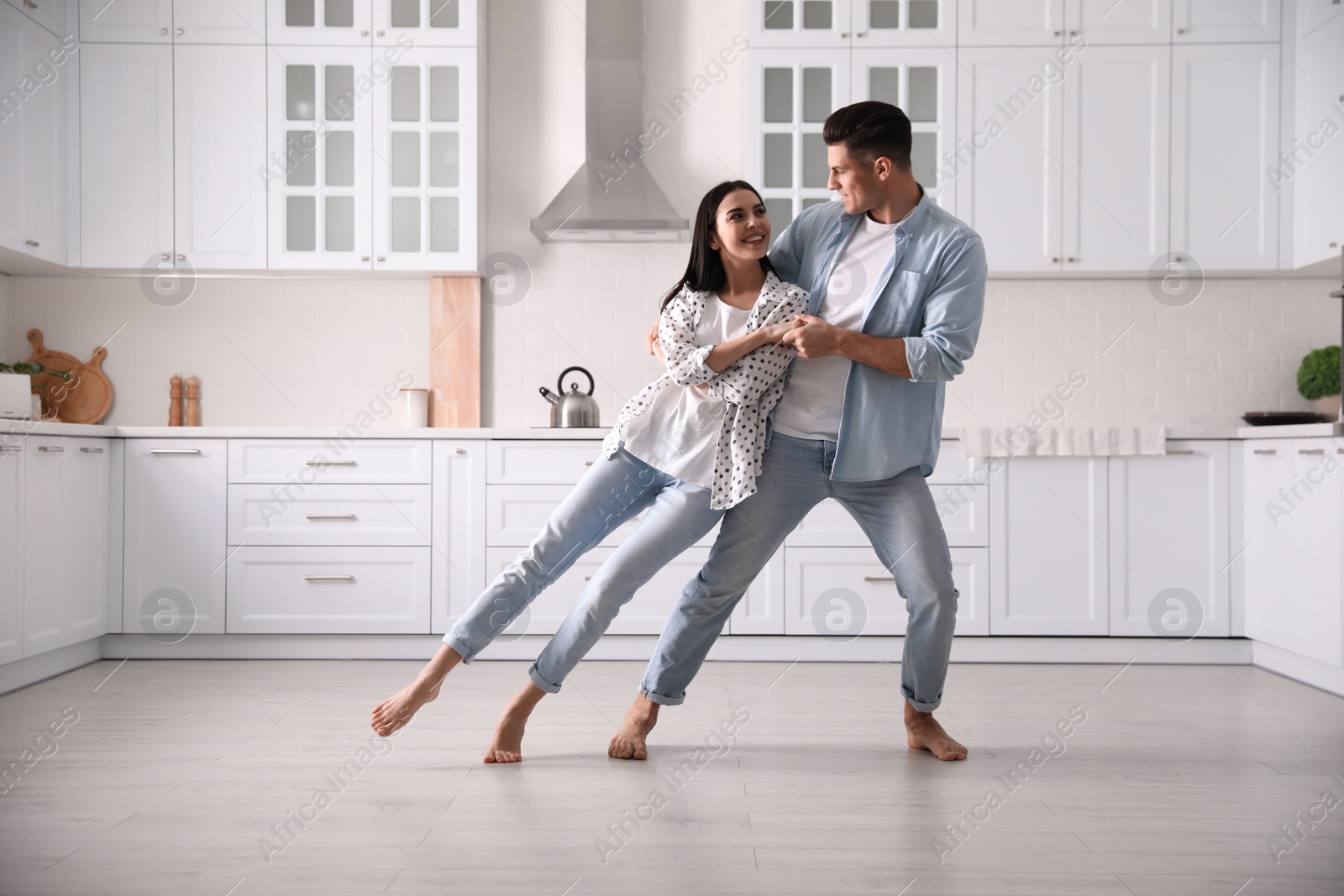 Photo of Happy couple dancing barefoot in kitchen. Floor heating system