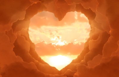 Beautiful sunset, view through heart shaped gap formed from orange clouds on sky