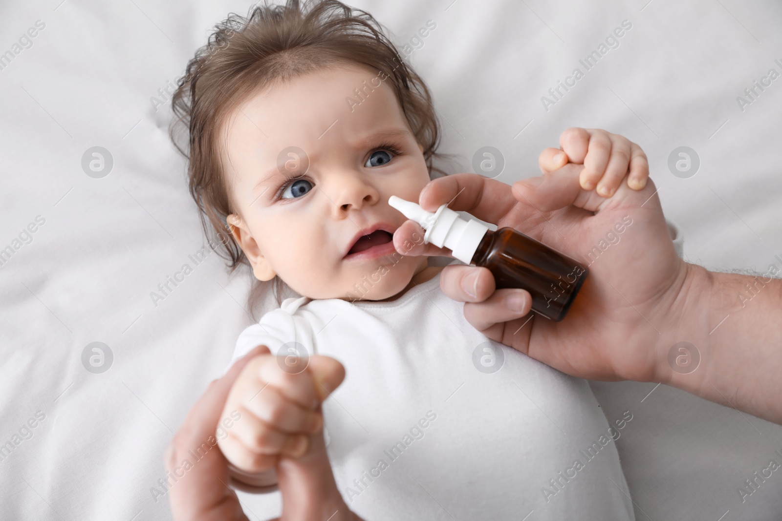 Photo of Father taking care of little baby suffering from runny nose in bed, top view