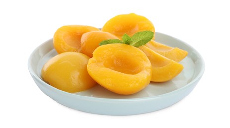 Plate with canned peach halves and mint leaves isolated on white