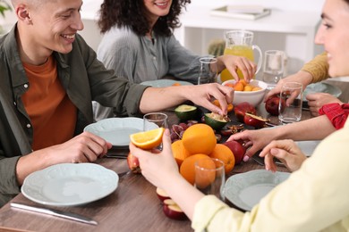 Friends eating vegetarian food at wooden table indoors