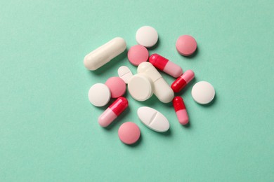 Photo of Pile of different pills on green background, flat lay