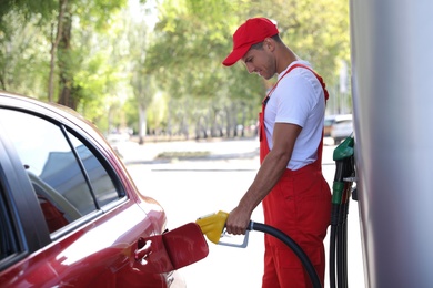 Worker refueling car at modern gas station