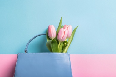 Photo of Flat lay composition with stylish woman's handbag and spring flowers on color background, space for text