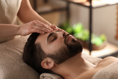 Young man receiving facial massage in beauty salon