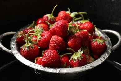 Metal colander with fresh wet strawberries in sink, closeup