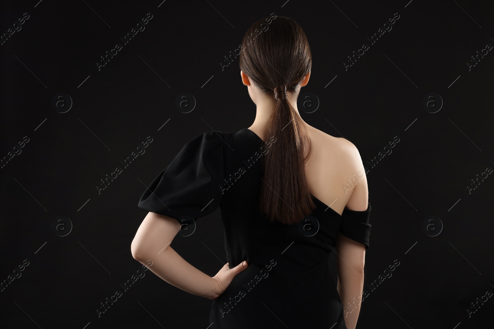 Photo of Woman in elegant dress on black background, back view