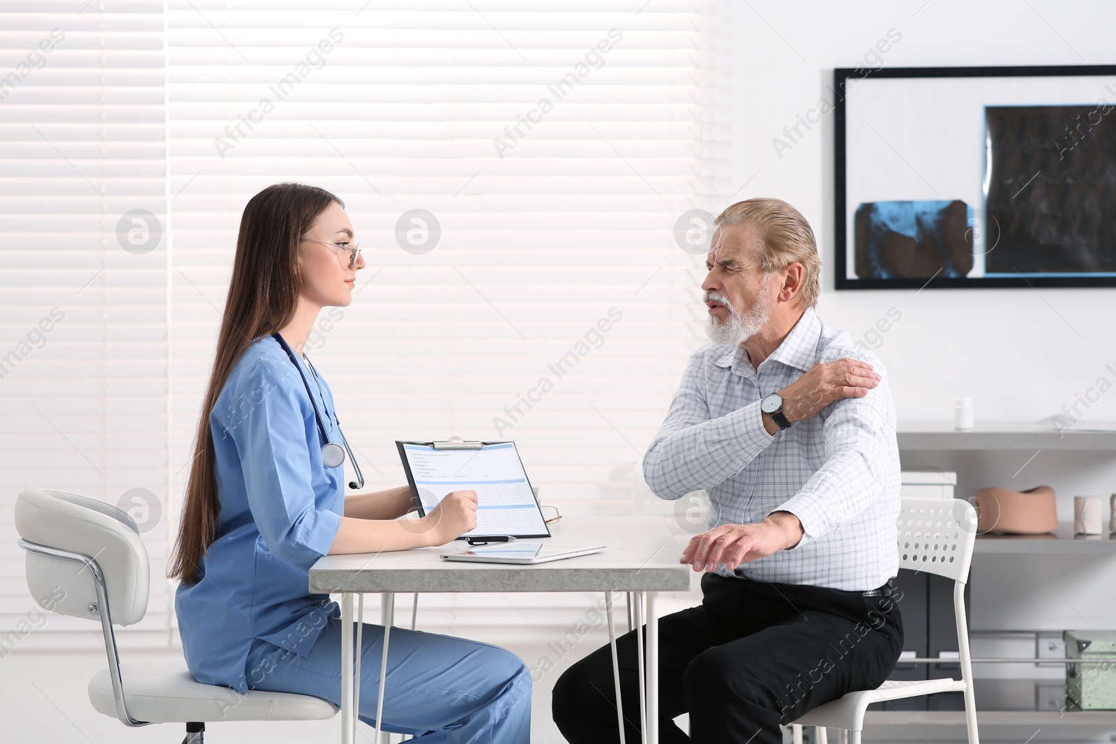 Photo of Orthopedist examining patient with injured arm in clinic