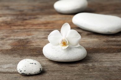 Photo of Spa stones and orchid on wooden table