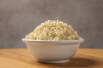 Bowl of hot noodles on table against grey background