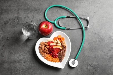 Photo of Flat lay composition with plate of products for heart-healthy diet on grey background