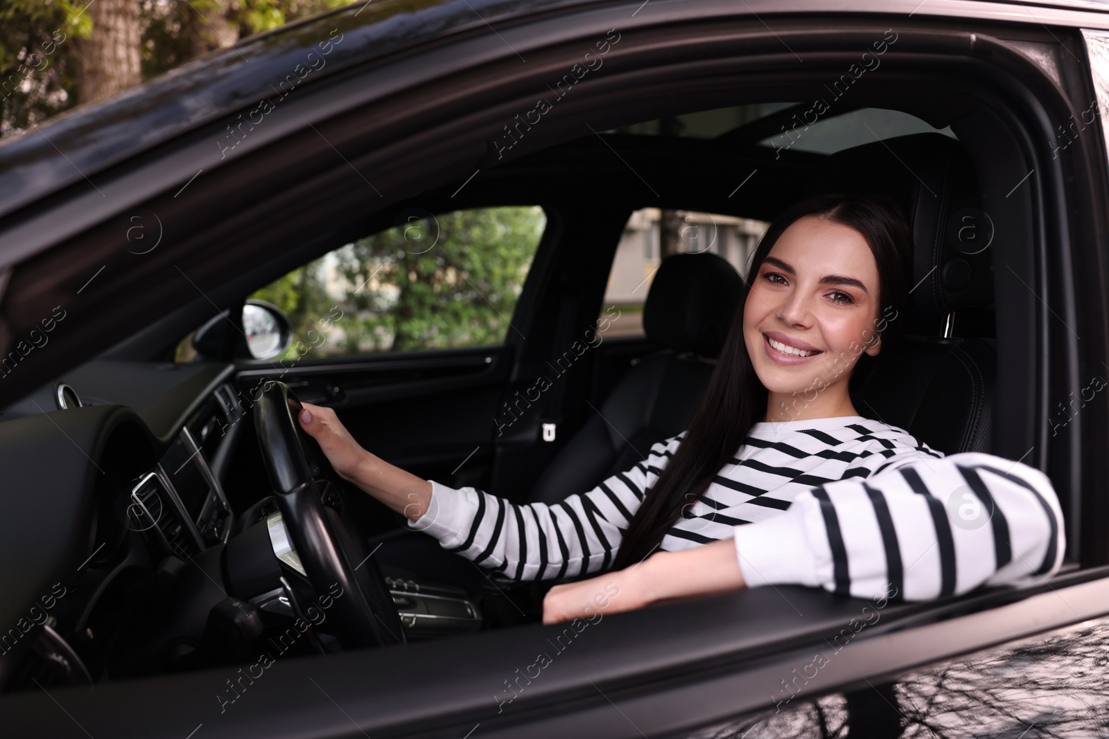 Photo of Young woman sitting inside her modern car