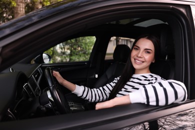 Photo of Young woman sitting inside her modern car