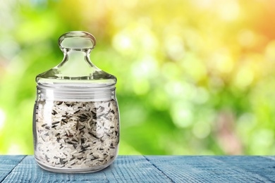 Image of Jar with rice on blue wooden table against blurred background, space for text