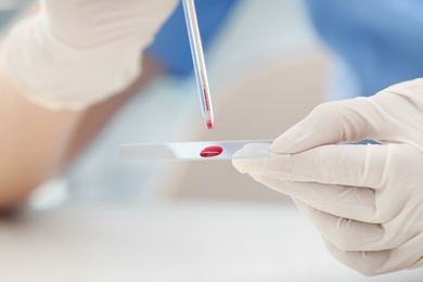 Scientist dripping blood sample on glass in laboratory