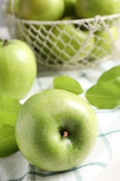Photo of Fresh ripe green apples with leaves and napkin on table, closeup