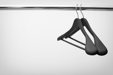 Photo of Clothes hangers on metal rail against light background