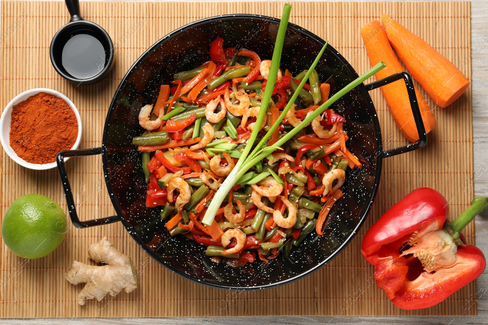 Photo of Shrimp stir fry with vegetables in wok and ingredients on table, flat lay