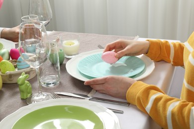 Photo of Woman setting table for festive Easter dinner at home, closeup