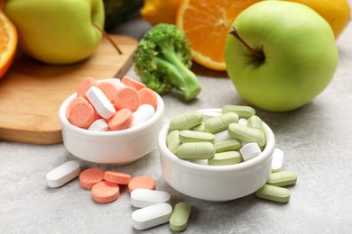 Photo of Dietary supplements. Different pills in bowls and food products on grey table