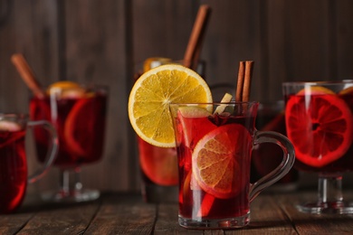 Photo of Glassware with red mulled wine on table against wooden background