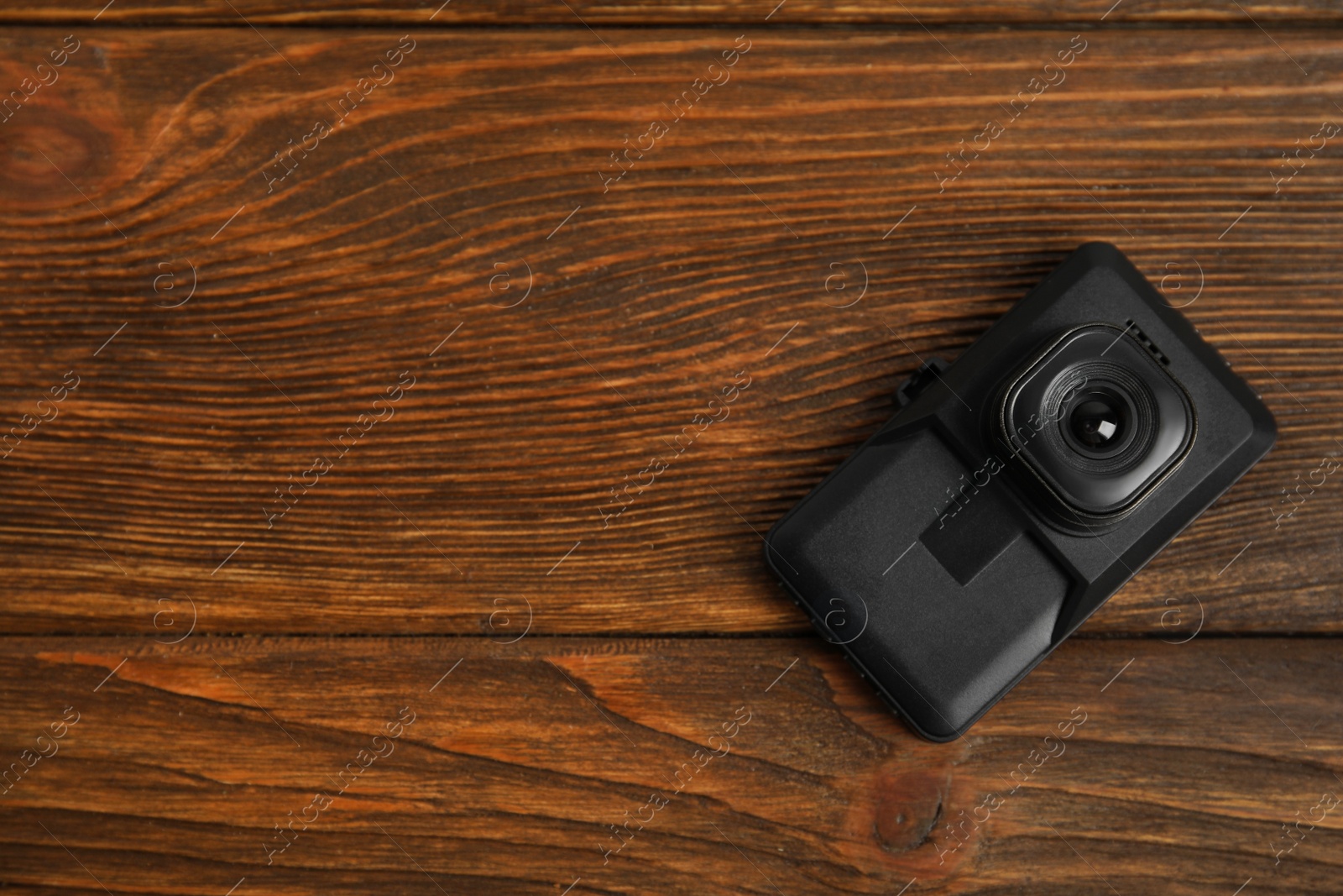 Photo of Modern car dashboard camera on wooden background, top view. Space for text