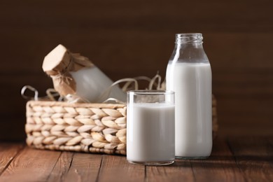 Photo of Tasty fresh milk in bottles and glass on wooden table