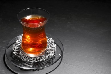 Glass with traditional Turkish tea on black table, closeup. Space for text