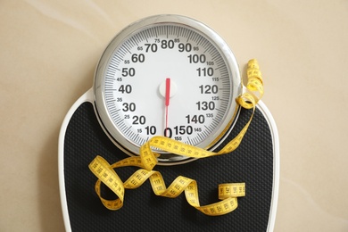 Photo of Scales and measuring tape on floor, top view. Overweight problem