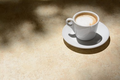 Cup of hot aromatic coffee on beige table. Space for text
