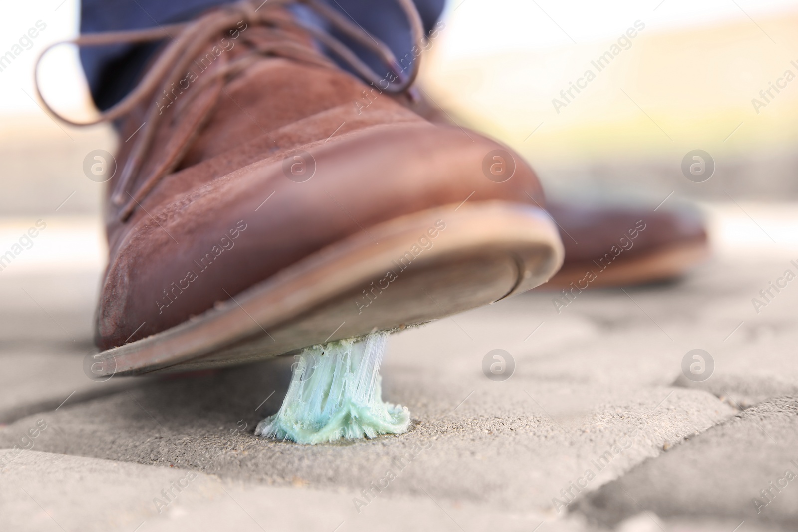 Photo of Man stepping in chewing gum on sidewalk. Concept of stickiness