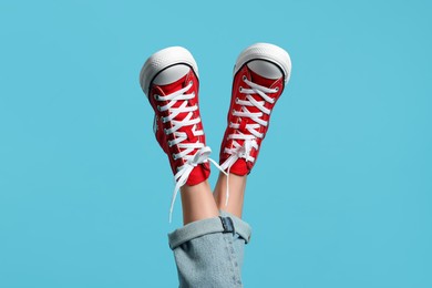 Photo of Woman in stylish gumshoes on light blue background, closeup