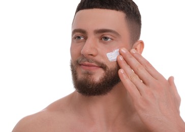 Handsome man applying cream onto his face on white background