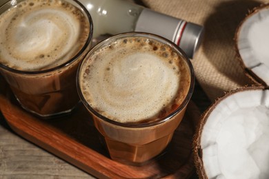 Photo of Glasses of tasty coffee with coconut syrup on wooden table, closeup