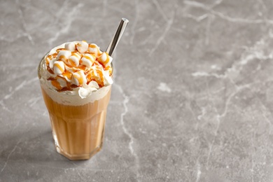 Photo of Glass with delicious caramel frappe on grey background