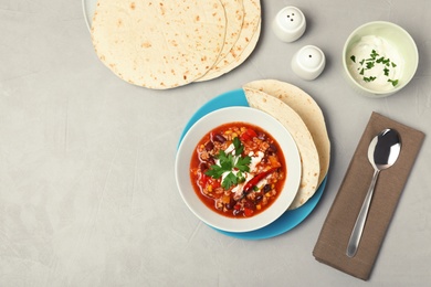 Delicious chili con carne served on gray table, flat lay. Space for text