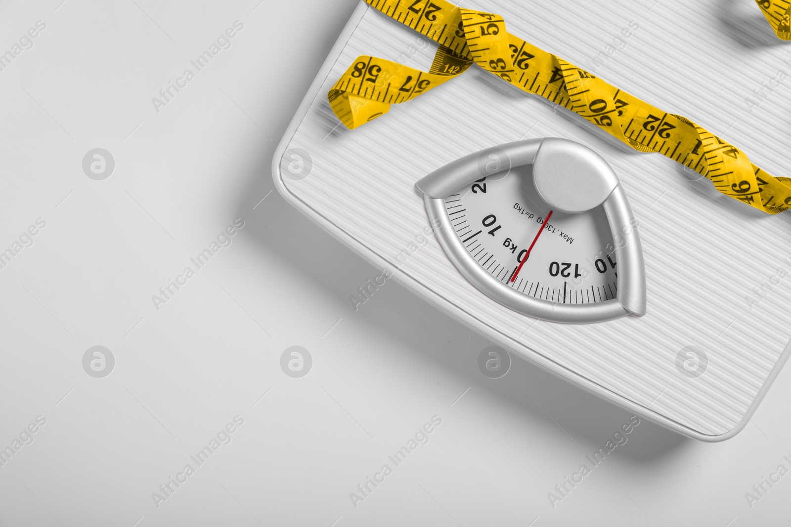 Photo of Weight loss concept. Scales and measuring tape on white background, top view. Space for text