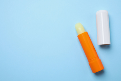 Photo of Hygienic lipsticks on light blue background, flat lay. Space for text